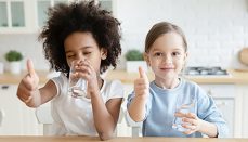 Two kids giving thumbs up to purified water